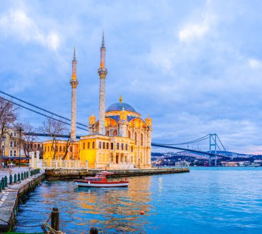 Ortakoy Camii, İstanbul, İstanbul 'daki İstanbul Köprüsü' nün yüksek açıklığı altında akşam ışığında parlıyor