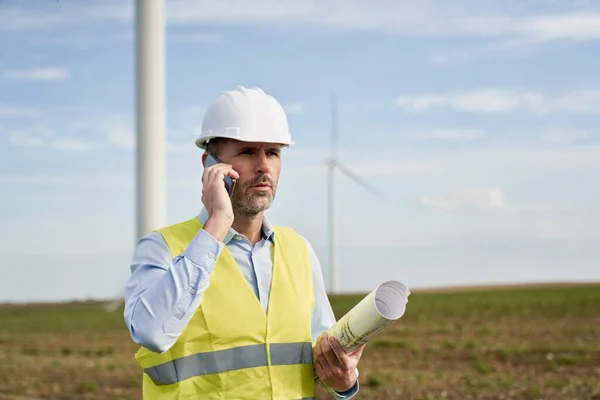 站在风力涡轮机场与电话交谈的白人男性工程师 — 图库照片