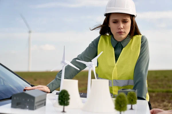 女高加索工程师站在室外检查风力涡轮机场塑料模型 — 图库照片