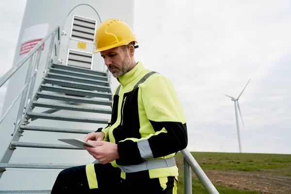 高加索工程师手持数码平板 站在风力涡轮机旁边 — 图库照片