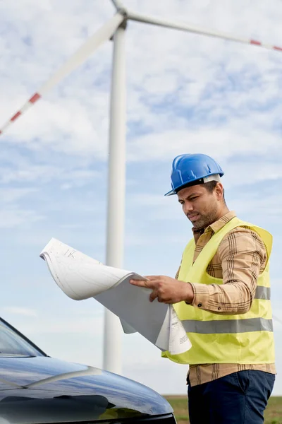 拉丁男性工程师站在风力涡轮机场检查用纸项目 — 图库照片