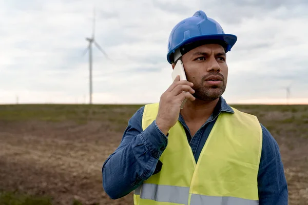 拉丁男性工程师站在风力涡轮机场 在电话中交谈 — 图库照片