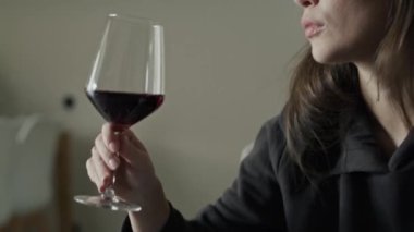 Evde kırmızı şarap içen beyaz bir kadın. 8K 'da kırmızı helyum kamerayla çekildi..  