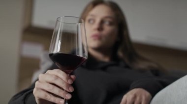 Evde kırmızı şarap içen üzgün, beyaz bir kadın. 8K 'da kırmızı helyum kamerayla çekildi..   