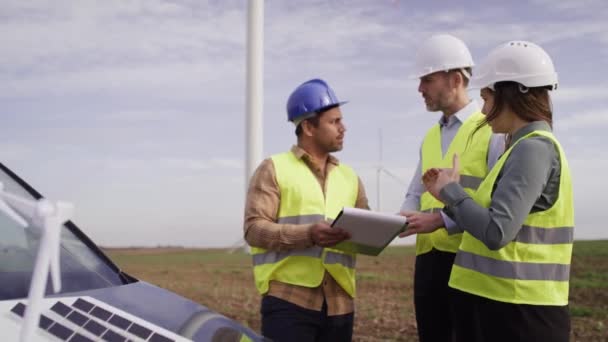 Trois Ingénieurs Caucasiens Latins Tenant Debout Sur Champ Des Éoliennes — Video