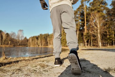 Düşük açı ve kışın gölün kıyısında koşan tanınmayan bir adamın dikiz açısı.