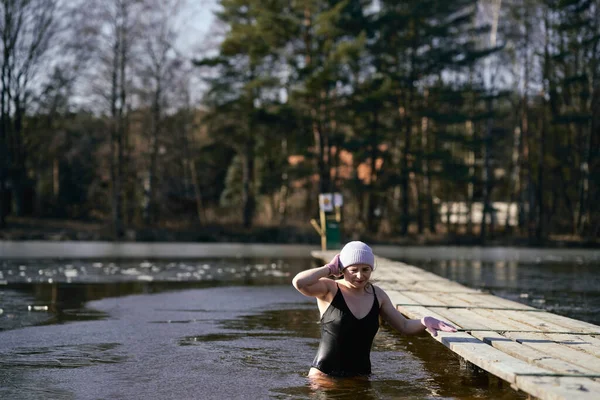 白种人年轻女子在冬泳后离开冰湖 — 图库照片