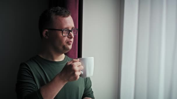 沉思的高加索男人与唐氏综合征在客厅喝咖啡 用8K的红色氦相机拍摄 — 图库视频影像