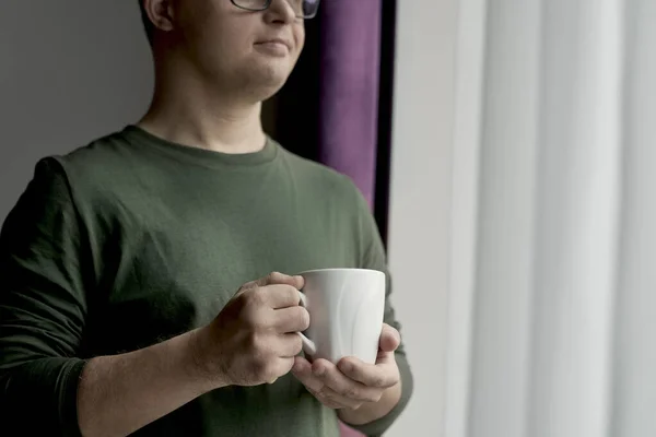 Pensive Kavkazský Muž Downovým Syndromem Stojící Šálkem Kávy Obývacím Pokoji — Stock fotografie
