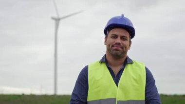 Rüzgâr türbini sahasında dikilen Latin profesyonel bir adamın portresi. 8K 'da kırmızı helyum kamerayla çekildi..   