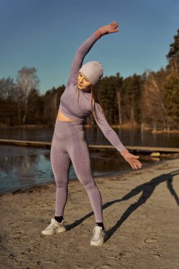 Sarışın beyaz kadın kışın dışarıda elleri havada ısınıyor. 