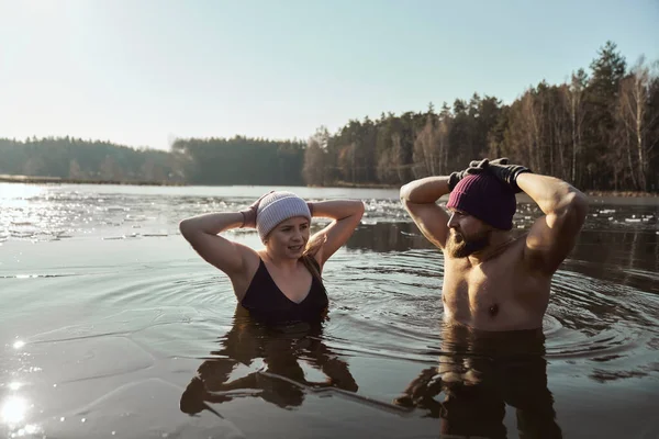 手を上げて凍った湖に立つ白人夫婦 — ストック写真
