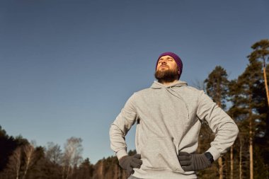 Beyaz bir adam kışın açık havada nefes alıyor ve güneş ışınları yakalıyor.