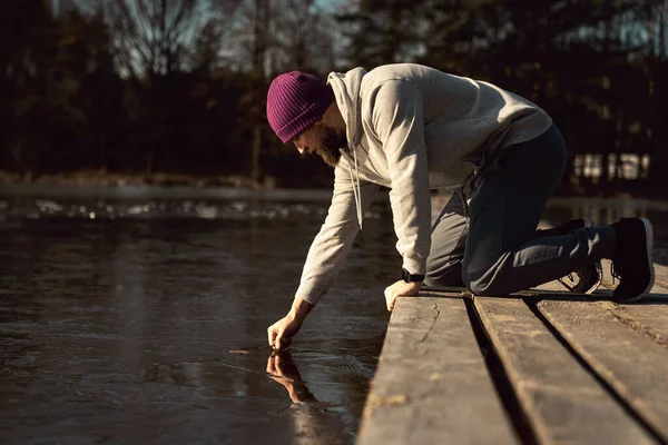 白种人成年男子在冰冷的湖中检查冰是否能游泳 — 图库照片