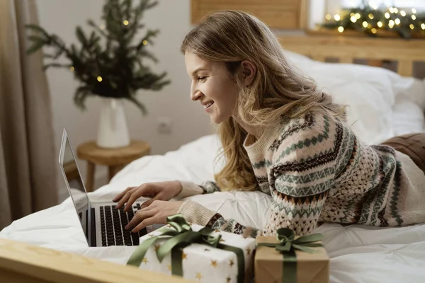 Caucasian Woman Lying Bed Front Browsing Laptop Christmas Presents — Stock Photo, Image
