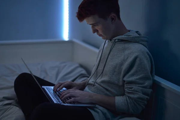 Foco Adolescente Caucasiano Usando Laptop Enquanto Sentado Noite Seu Quarto — Fotografia de Stock