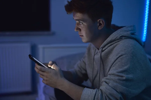 Figyelmes Kaukázusi Tinédzser Fiú Mobiltelefont Használ Miközben Éjszakánként Szobájában Félrenéz — Stock Fotó