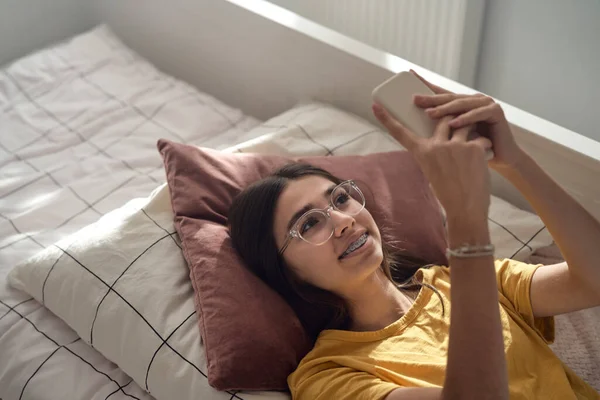 Ovanifrån Kaukasisk Tonåring Flicka Bläddrar Telefon När Hon Ligger Sängen — Stockfoto