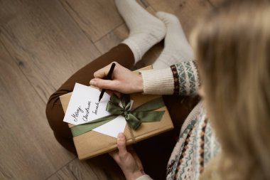 Kafkasyalı bir kadının yere oturup Noel kartı yazmasının en iyi görüntüsü. 