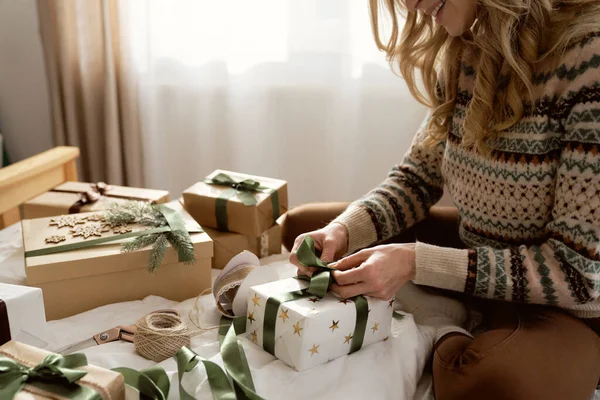 无法辨认的高加索女人坐在床上 在家里包装圣诞礼物 — 图库照片