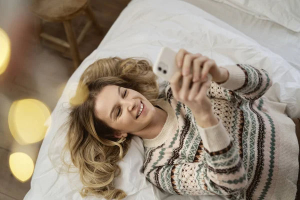 在圣诞礼物中 高加索女人躺在床上用手机拍照的头像 — 图库照片