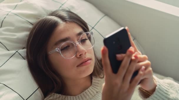Sluiten Van Kaukasische Tienermeisje Browsen Telefoon Terwijl Liggend Bed Haar — Stockvideo