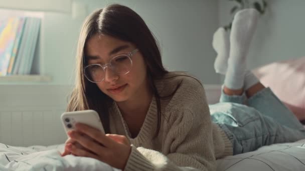 Blanke Tiener Meisje Browsen Telefoon Terwijl Liggen Voorkant Bed Opgenomen — Stockvideo