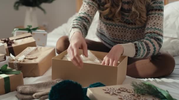 白人女性がベッドに座り ベッドルームでクリスマスプレゼントを梱包しています 8Kでレッドヘリウムカメラで撮影 — ストック動画