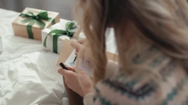 ベッドに座ってクリスマスカードを書いている白人女性のトップビュー 8Kでレッドヘリウムカメラで撮影 — ストック動画