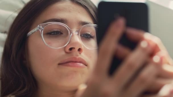 Zoom Caucasiano Adolescente Navegando Telefone Enquanto Deitado Cama Suas Costas — Vídeo de Stock