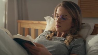 Kafkasyalı bir kadın sabah yatağa uzanıp kitap okuyor. 8K 'da kırmızı helyum kamerayla çekildi.. 