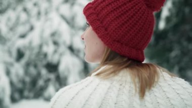 Caucasian woman wearing red hat walking in snowing forest. Shot with RED helium camera in 8K.