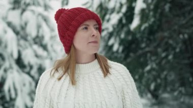 Caucasian woman wearing red hat walking in snowing forest. Shot with RED helium camera in 8K.