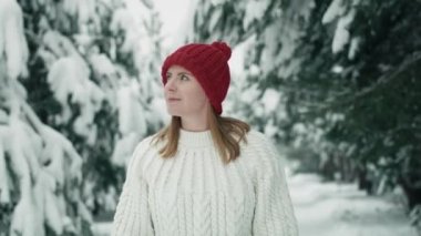 Caucasian woman wearing red hat walking in snowing forest. Shot with RED helium camera in 8K.