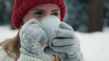 Close up of woman standing outdoors and drinking hot tea in winter outdoors. Shot with RED helium camera in 8K.   