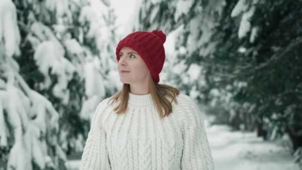 雪の森を歩く赤い帽子をかぶった白人女性 8Kでレッドヘリウムカメラで撮影 — ストック動画
