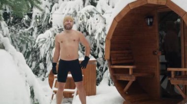Caucasian man warming up before winter swim in barrel. Shot with RED helium camera in 8K.