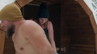 Caucasian couple come out of sauna and enter the barrel with frozen water. Shot with RED helium camera in 8K.     