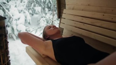 Caucasian woman enjoying in the sauna in winter. Shot with RED helium camera in 8K