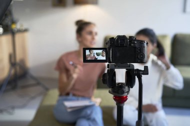 Selective focus on two female vloggers recording a movie with home video camera