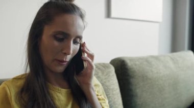 Kanepede oturan ve telefonda konuşan beyaz bir kadın. 8K 'da kırmızı helyum kamerayla çekildi..  