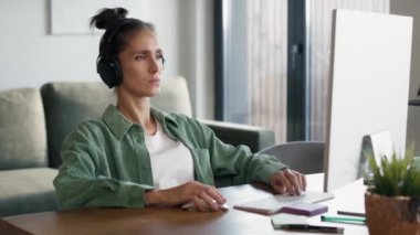 Focus young caucasian woman wearing headphones and working on computer. Shot with RED helium camera in 8K. 