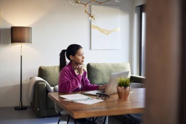 Woman in purple jacket working on computer at home