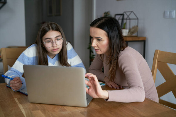 Caucasian mother with teenager daughter make homework at home