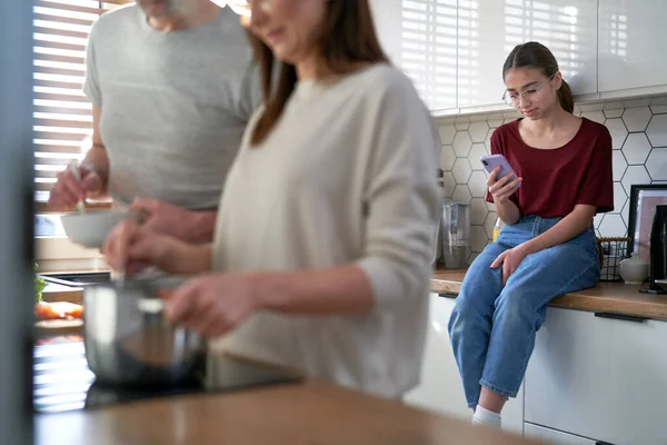Teenage Daughter Using Mobile Phone Kitchen Parents Cooking Together — Fotografia de Stock