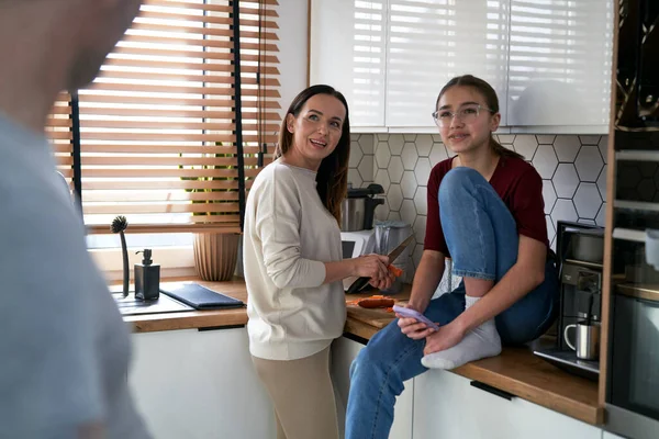 Caucasian teenager girl with mom talking with father in the kitchen