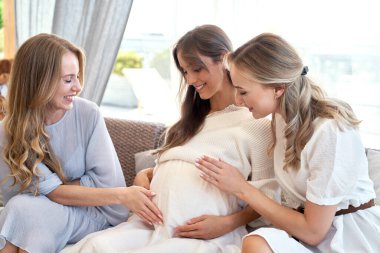 Female friends spending time together during the pregnancy one of them