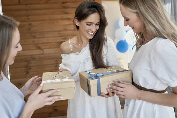 Group of caucasian women giving gifts to friend in pregnant