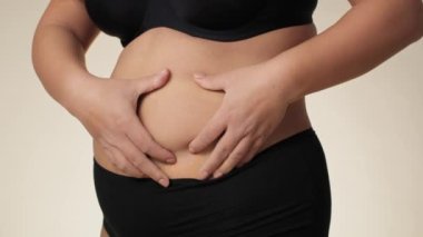 Unrecognizable plus size woman touching and pressing her belly. Shot with RED helium camera in 8K. 