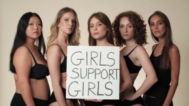 Stüdyoda elinde pankartla iç çamaşırlı bir grup kadının portresi. 8K 'da kırmızı helyum kamerayla çekildi.. 